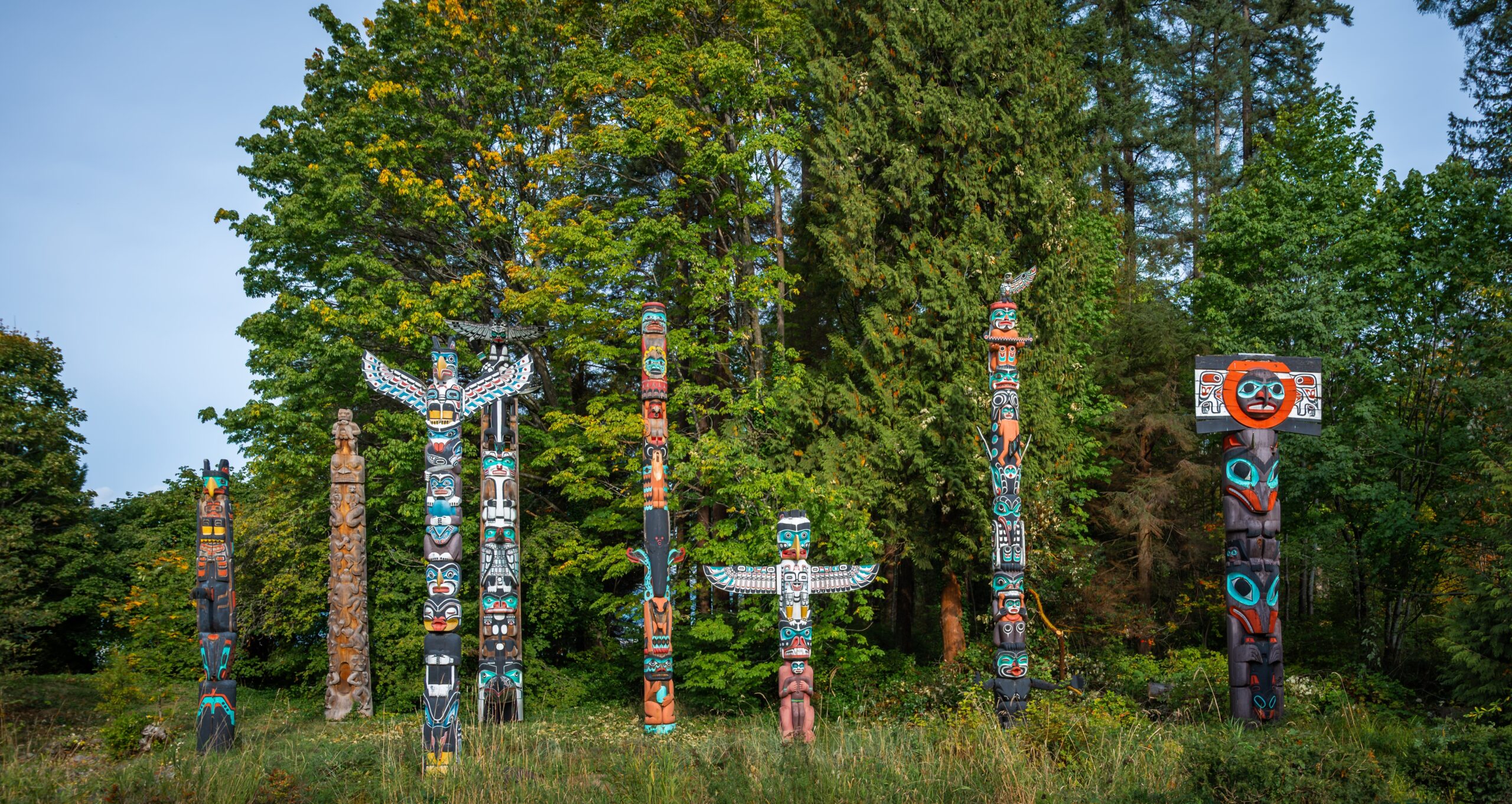 Colourful,Totem,Poles,Stand,Proudly,In,A,Lush,Forest,,Representing